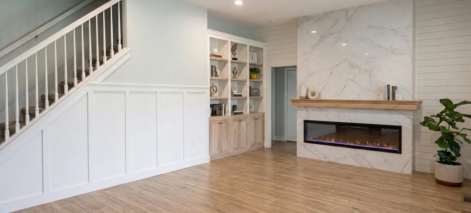 Custom white living-room built-ins beside a porcelain fireplace surround with a wood mantel and shiplap accent wall