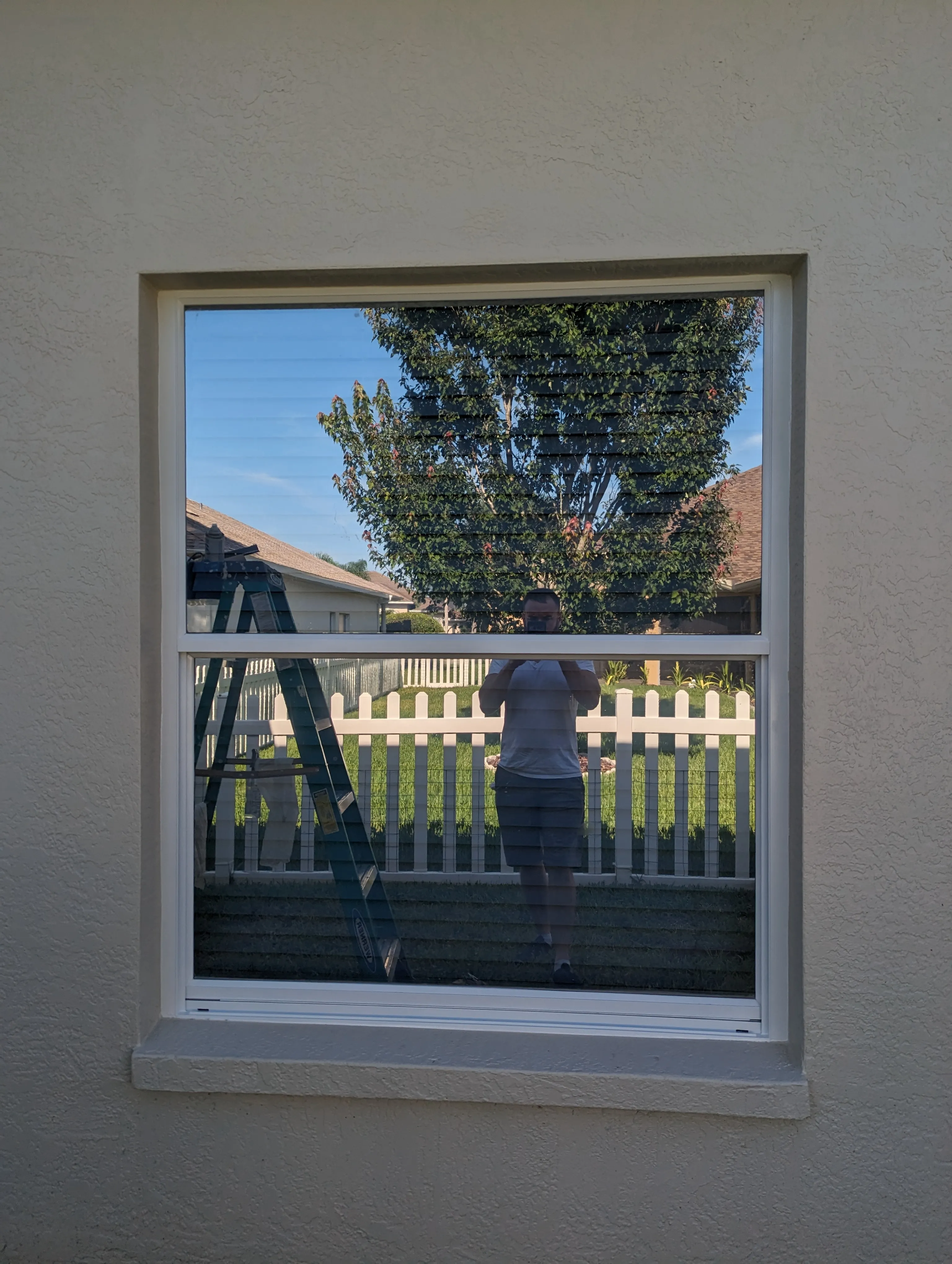 After: Exterior aluminum window frame masked and prepped, then repainted crisp white against a fresh stucco wall